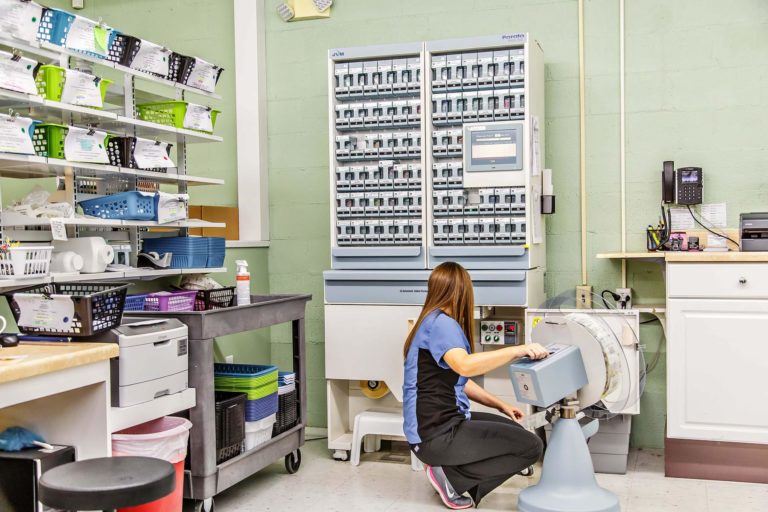 Technician at Wolfe's pharmacy attends to the lower packaging unit of the PASS 208